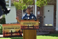 A man, Xavier Becerra, stands behind a podium behind a sign that reads "Protecting Communities from Extreme Heat"