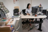 A photo of a woman sitting at a desk, working at a computer.