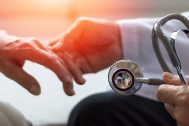 A photo of a geriatrician holding an elderly patient's hand.