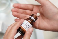 A photo of a person holding a tablet of ivermectin and a pill bottle.