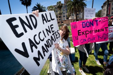 A photo of protesters holding signs that read, "End all vaccine mandates," and "Don't experiment on our kids."