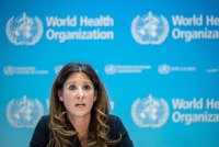 A photo of a woman at a press conference with the WHO logos seen behind her.