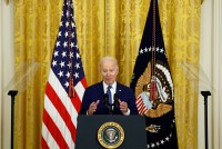 A photo of Biden speaking at a podium inside the White House.