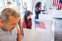 A photo of voters filling out ballots behind privacy dividers at a polling location.