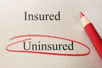 A photo of a piece of paper with the words "insured" and "uninsured" on it. "Uninsured" is circled with a red colored pencil.