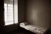 An empty prison cell with a bed in it.