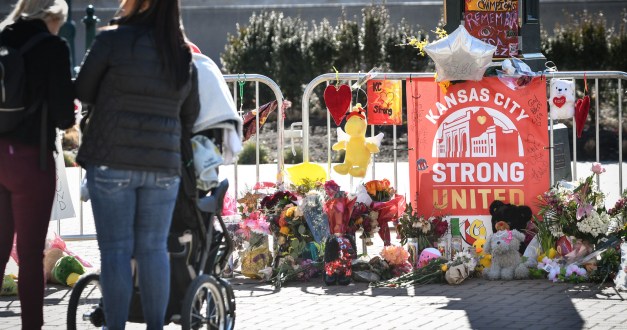 An outdoor memorial is sat up near Union Station in Kansas City. There is a sign that reads, "Kansas City / Strong / United." Flowers, stuffed animals, and other memorial gifts surround the sign.