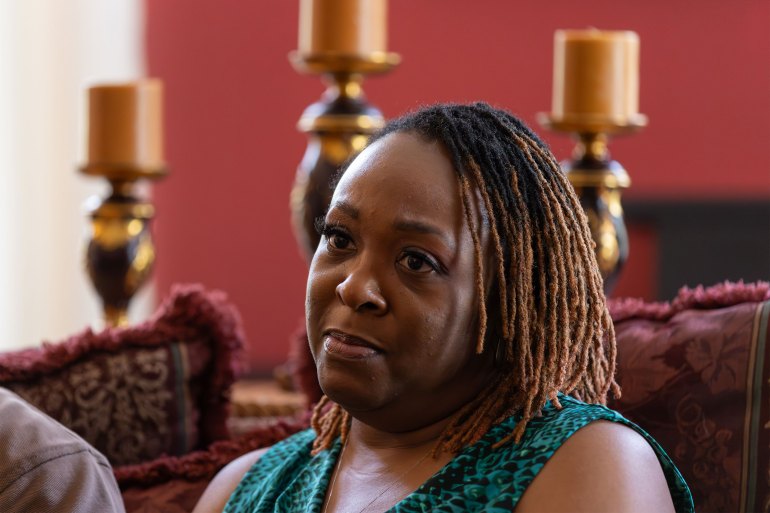 A photo of an older woman sitting and looking contemplative.