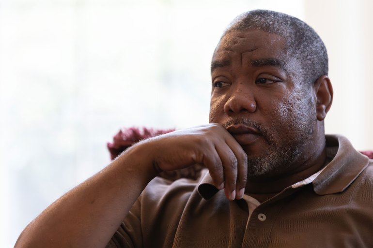 A photo of an older man sitting and looking contemplative.