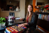 A portrait of Hannah Russell sitting at her computer desk. One hand is on her computer while her other hand is resting on a book titled, "Special Education Law."